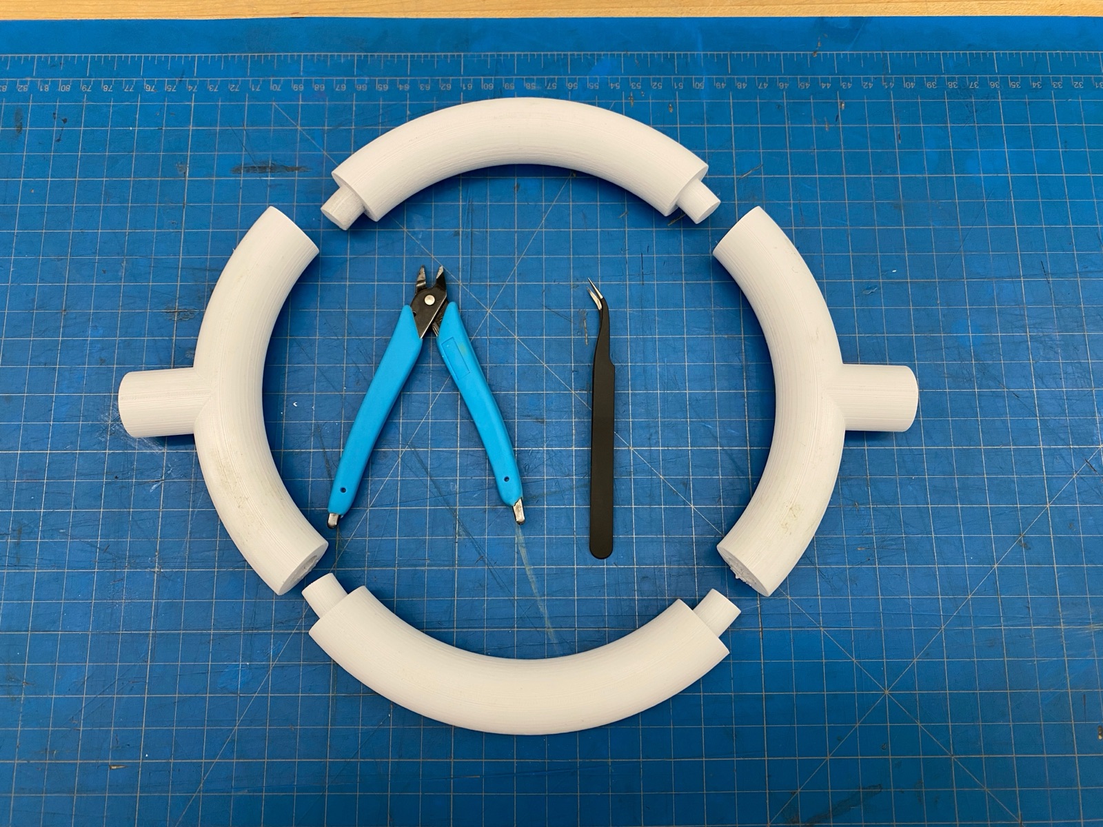 Four PLA quarter-sections of the ring laid out flat with the round pegs visible.