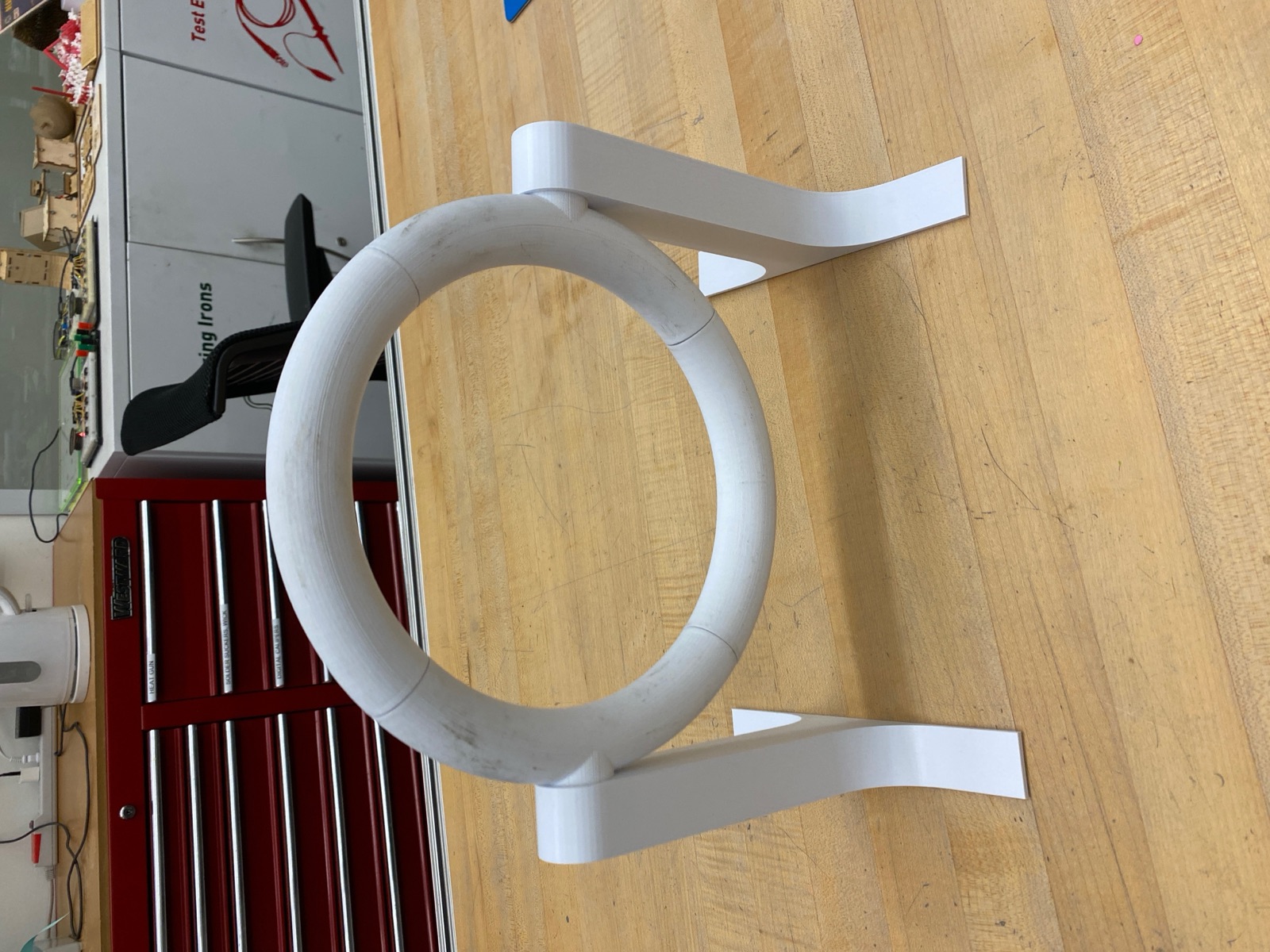 Assembled PLA prototype ring on white legs standing on a workbench.