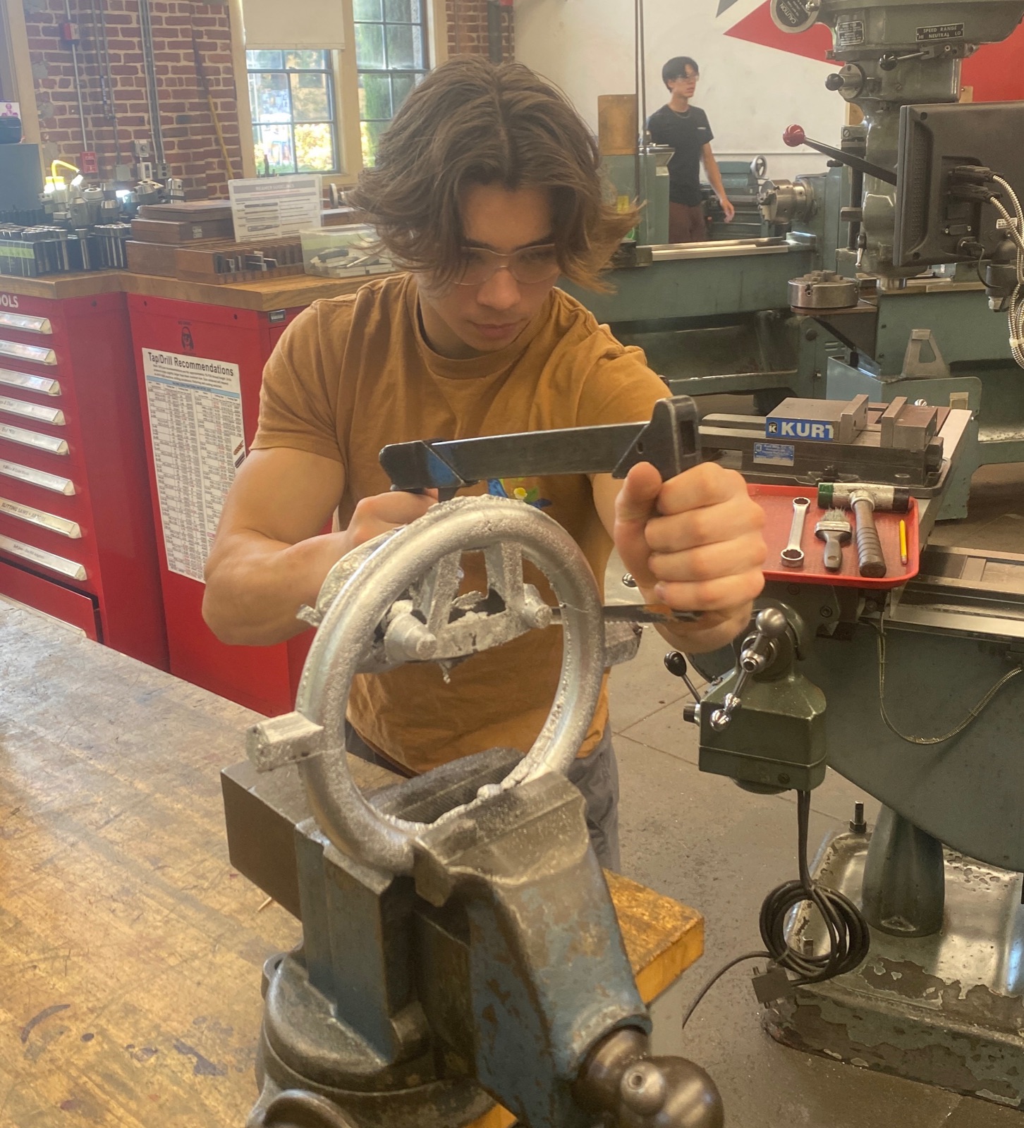 Cleaning up the casting in a vise with hand tools.