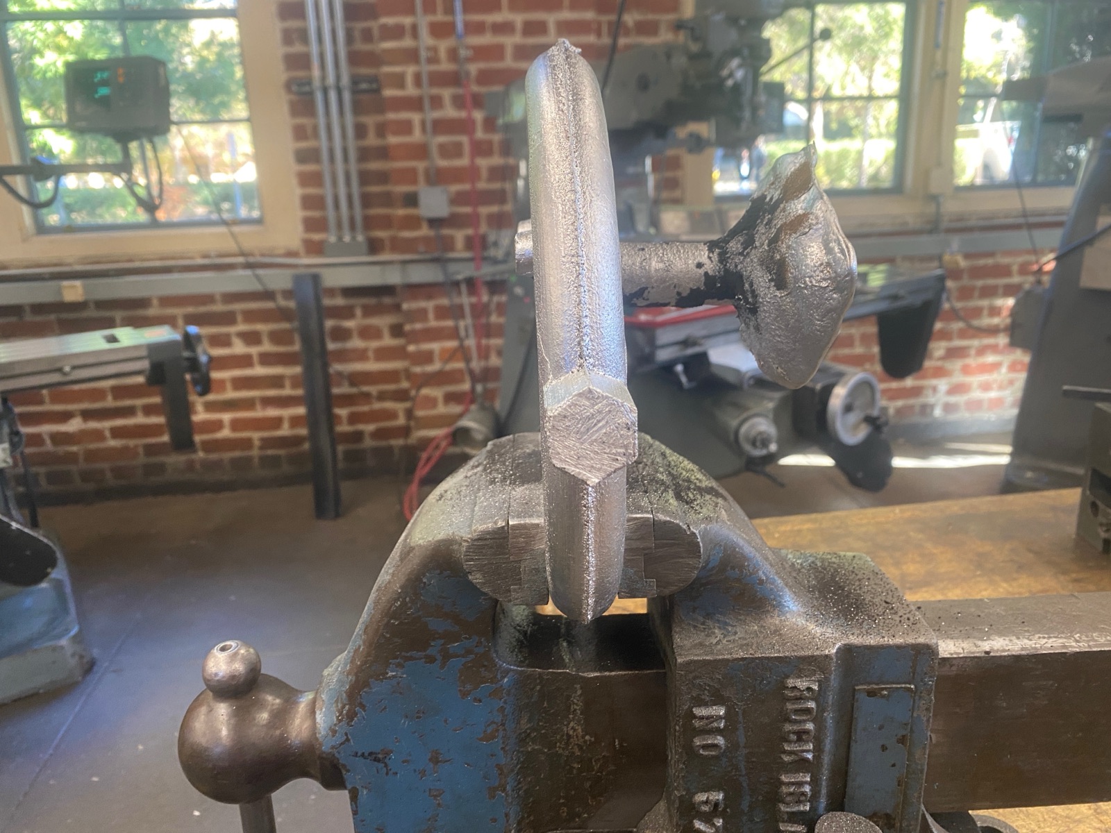 Close-up of the as-cast hex peg in a vise before grinding to tolerance.