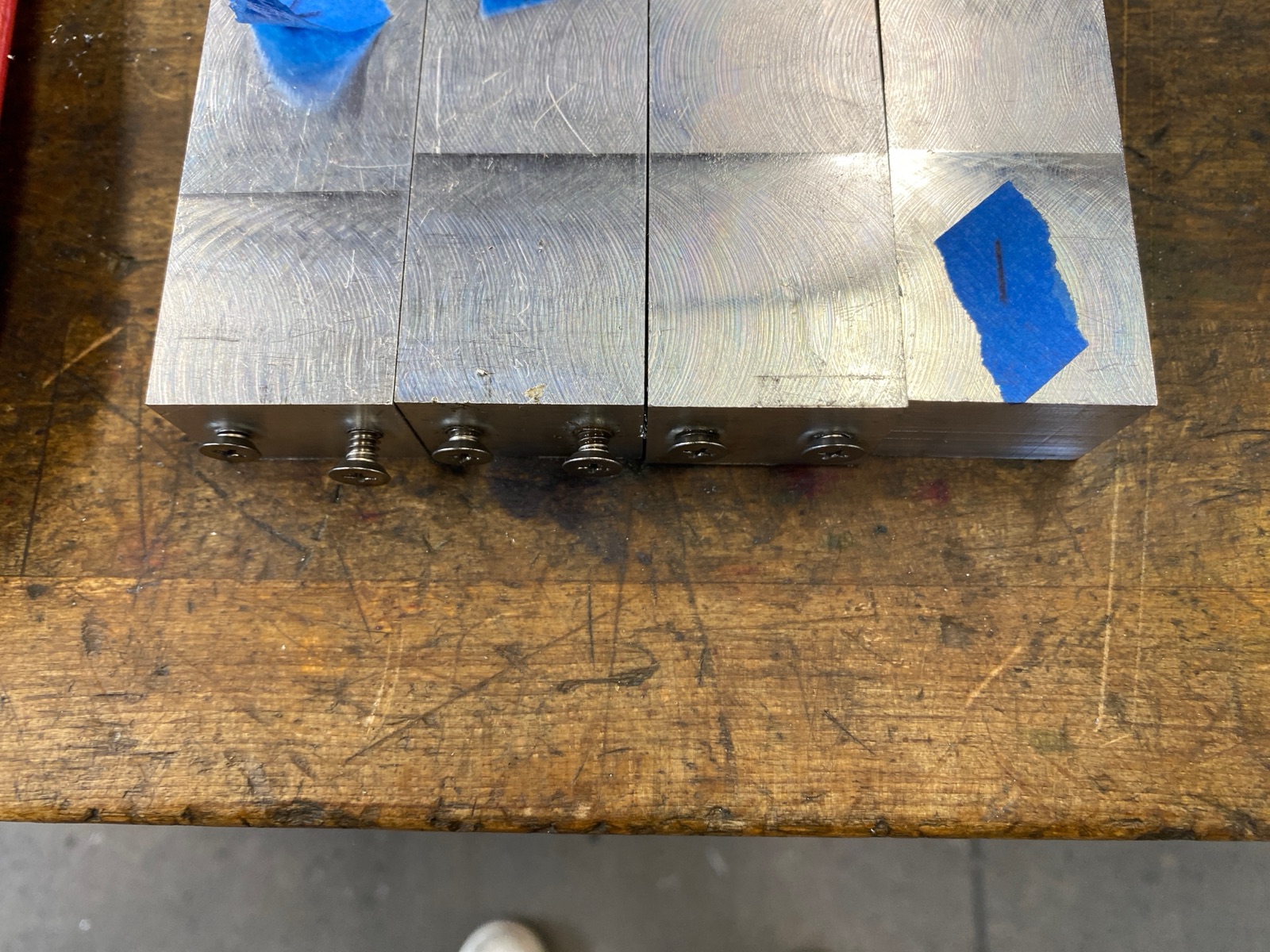 Top view of all four leg blanks lined up showing tapped screw holes.