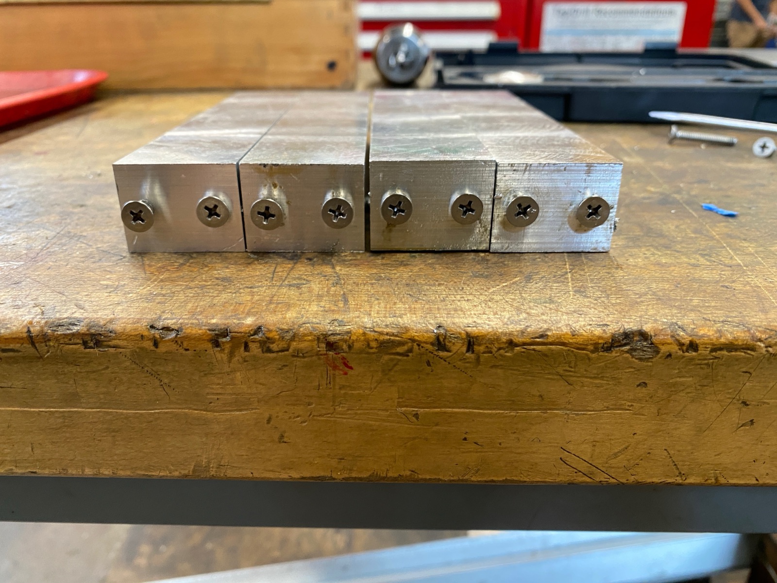 Side view of the four leg blanks with screws sitting in the tapped holes.