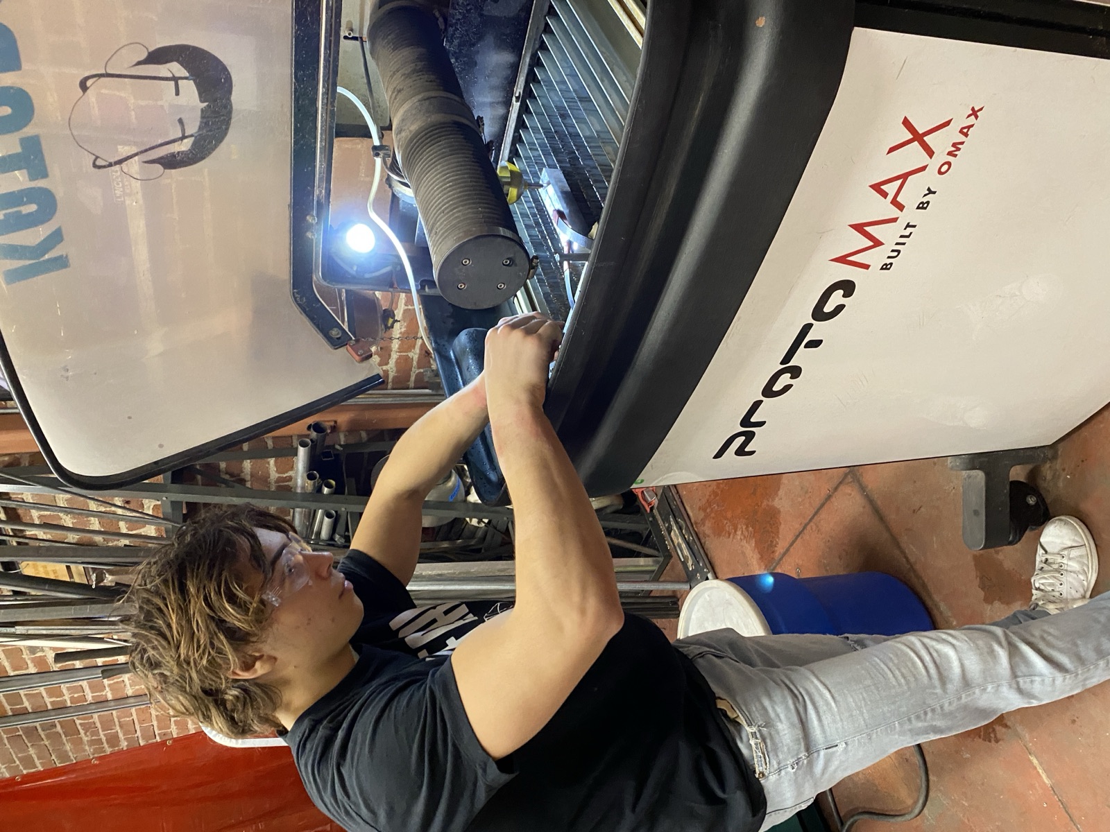 Operating the OMAX water jet to cut the hex hole in a leg.