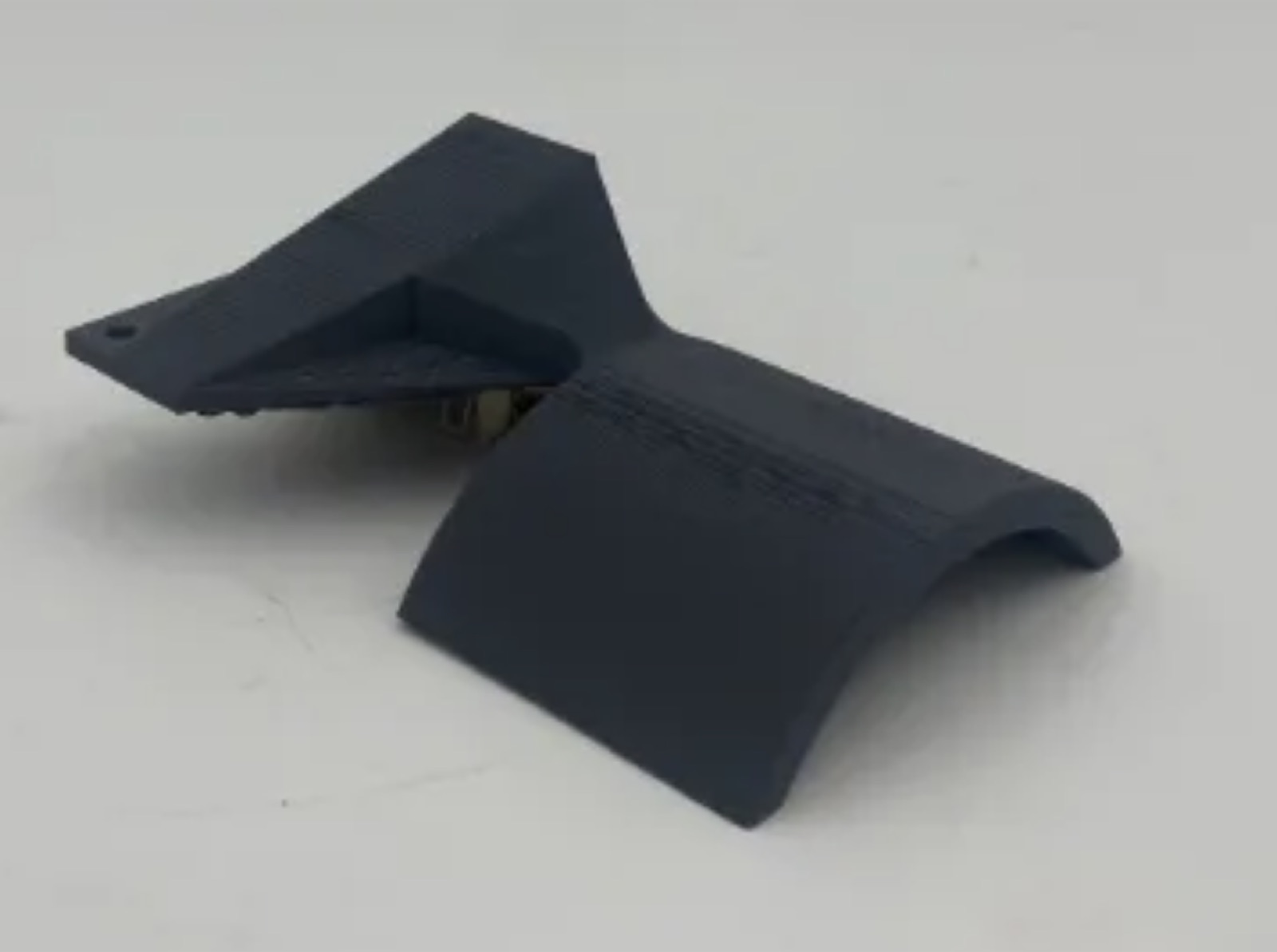 Multiple V1 PLA print iterations laid out on a blue cutting mat, showing the base plate and arc geometry refining across versions.