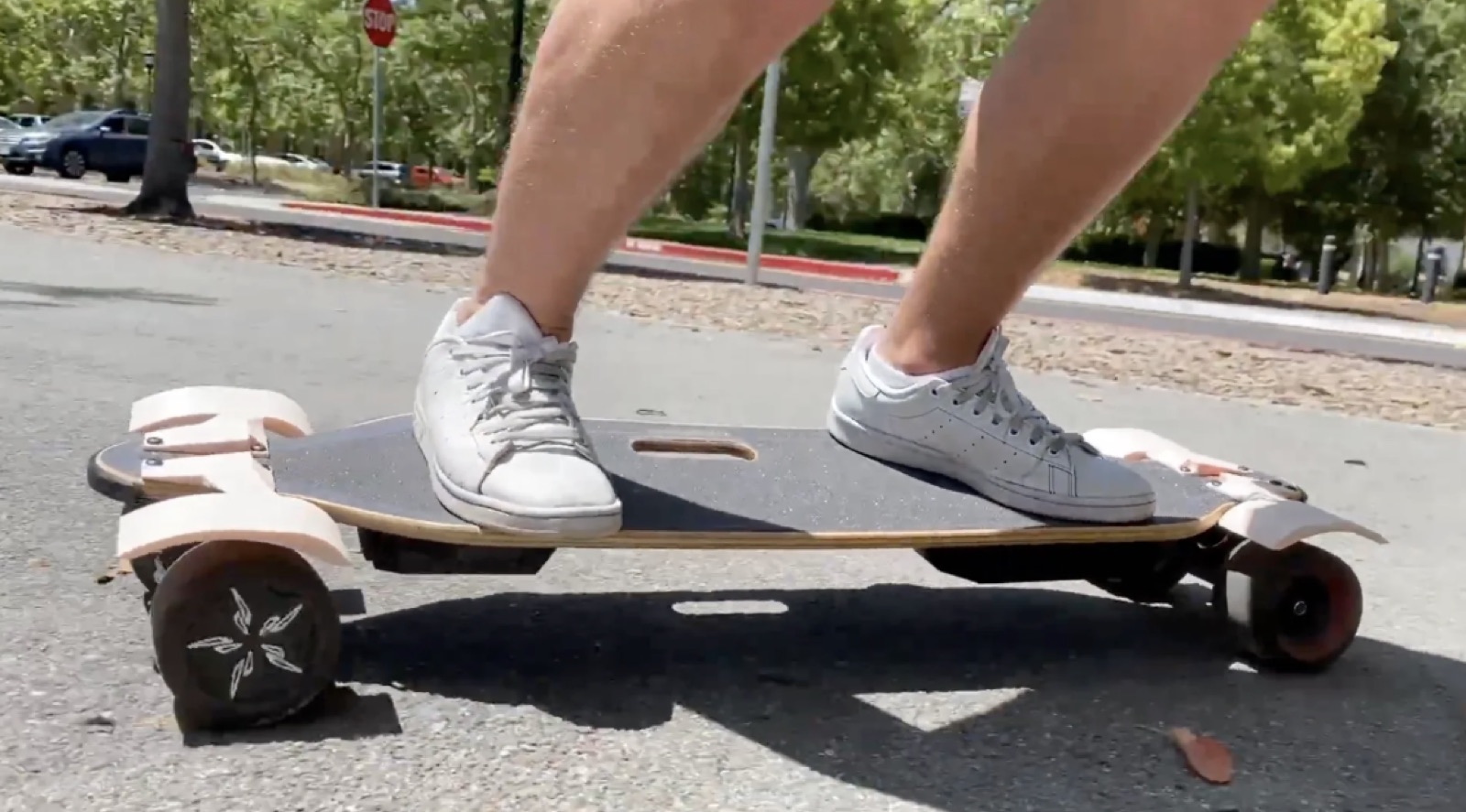 V1 WaterShield mounted on the longboard during a test ride, white fenders visible covering the wheels.