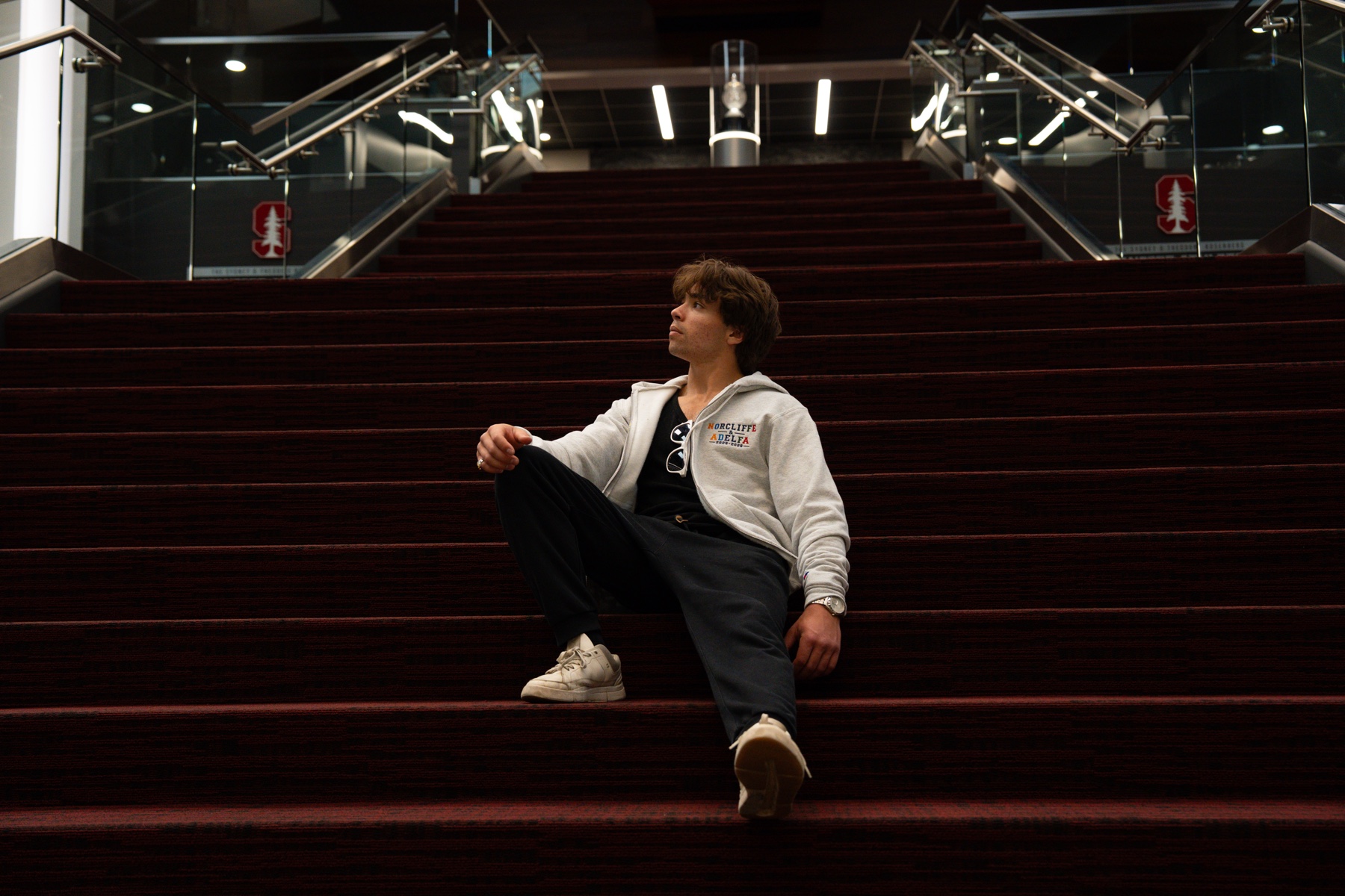 Seated on the red stairs in the hoodie